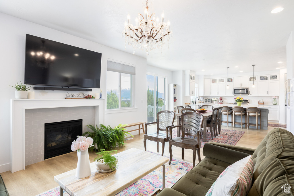 Living room with light wood-style floors, a chandelier, a fireplace, and recessed lighting