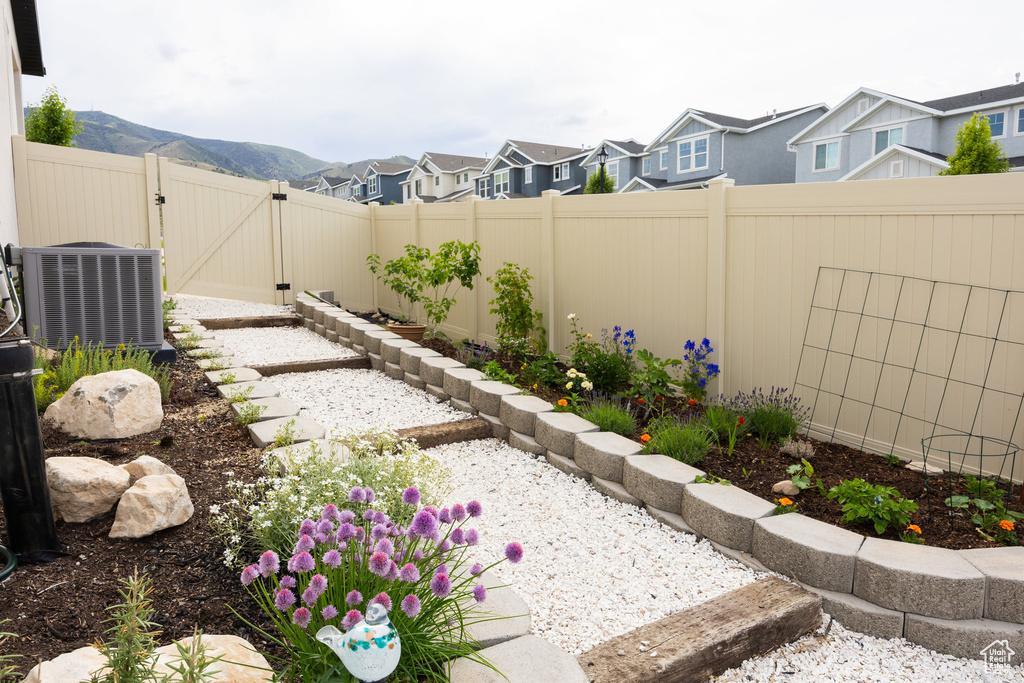 Fenced backyard featuring cooling unit, a gate, a residential view, and a mountain view