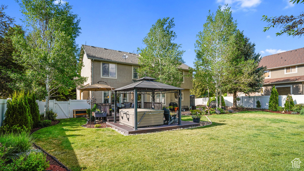 Back of property featuring a gazebo, stucco siding, and a hot tub