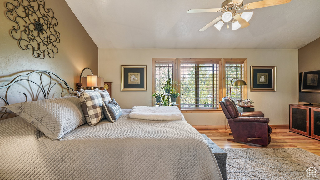 Bedroom with lofted ceiling, wood finished floors, baseboards, and ceiling fan