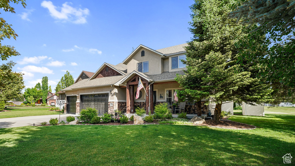 Craftsman inspired home featuring stucco siding, a garage, a front lawn, and stone siding