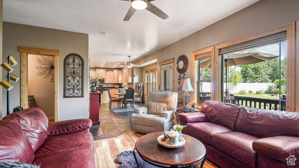 Living area featuring a ceiling fan, plenty of natural light, and light wood-type flooring