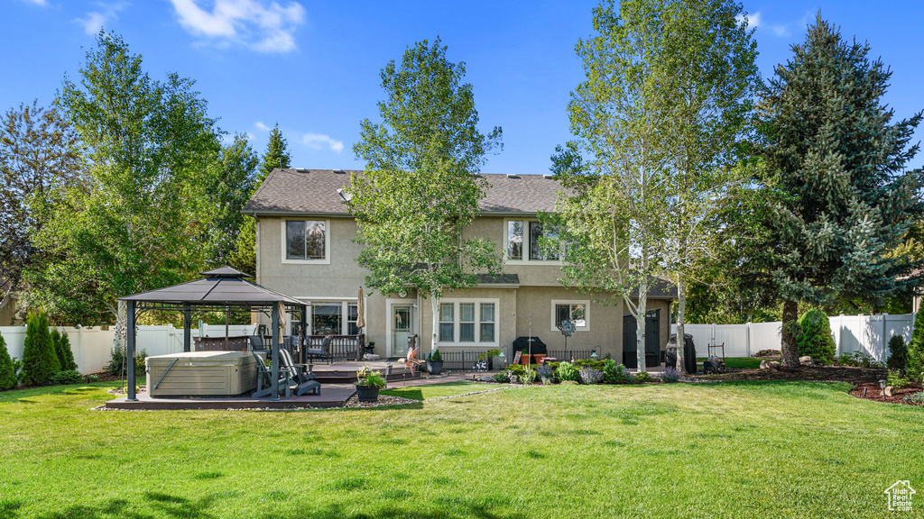 Back of property featuring a hot tub, a gazebo, stucco siding, and a patio area