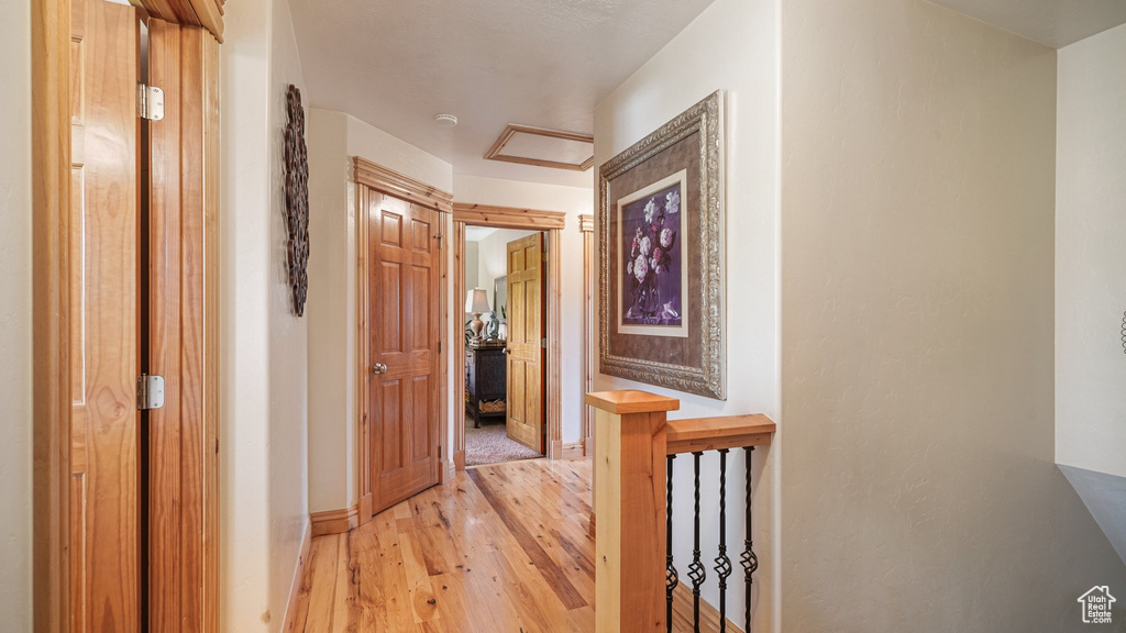 Hallway with light wood-style floors, baseboards, and an upstairs landing
