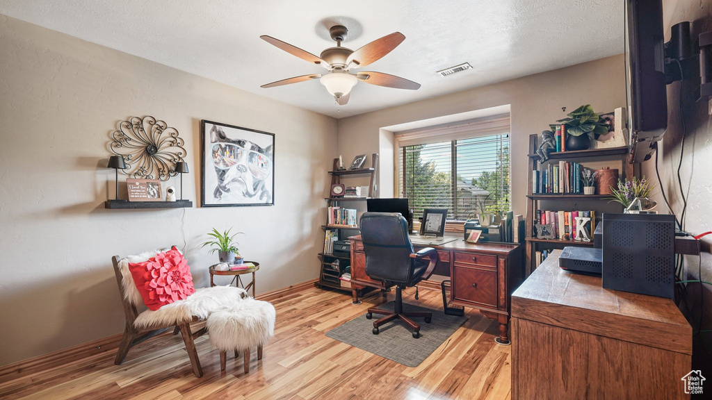 Office area with light wood-type flooring, a ceiling fan, and baseboards