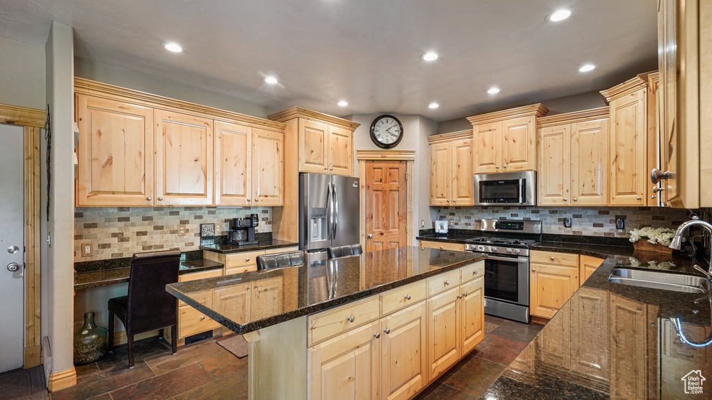 Kitchen featuring appliances with stainless steel finishes, a sink, light brown cabinets, a kitchen island, and recessed lighting