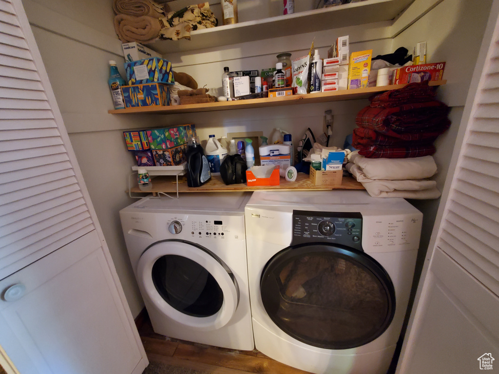 Laundry area with separate washer and dryer and wood finished floors