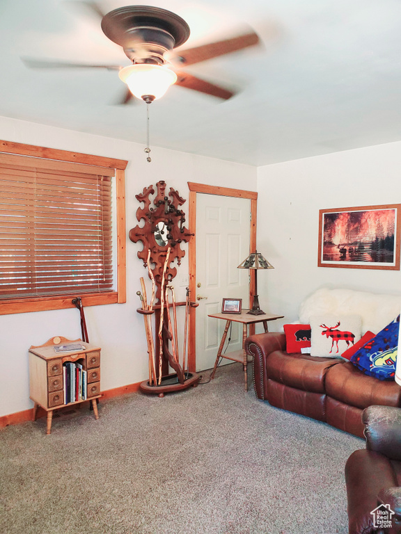 Living area featuring carpet floors, ceiling fan, and baseboards