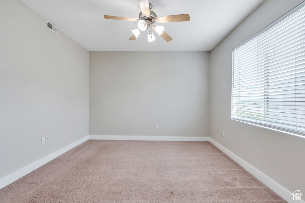 Unfurnished room featuring light carpet, ceiling fan, and baseboards