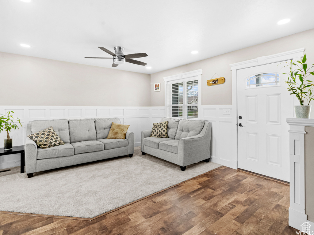 Living room featuring wood finished floors, ceiling fan, wainscoting, a decorative wall, and recessed lighting