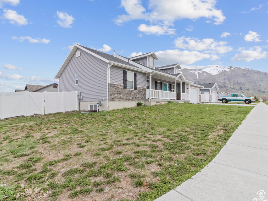 View of side of home featuring an attached garage, a porch, and a mountain view