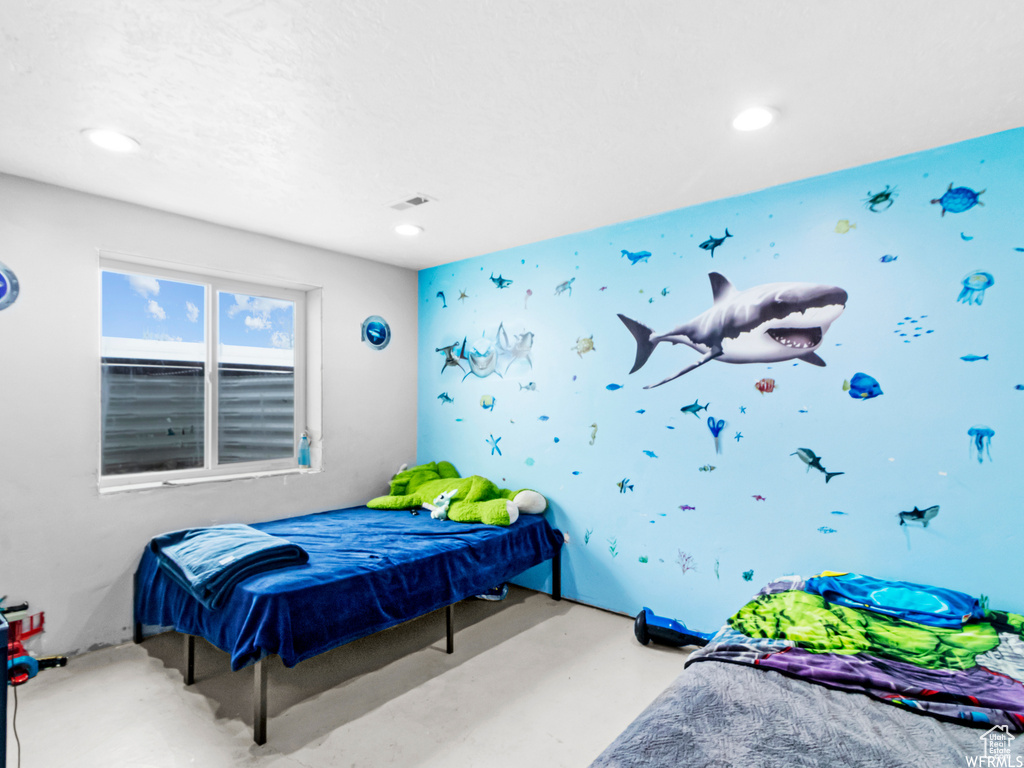 Bedroom with recessed lighting, wallpapered walls, and concrete flooring