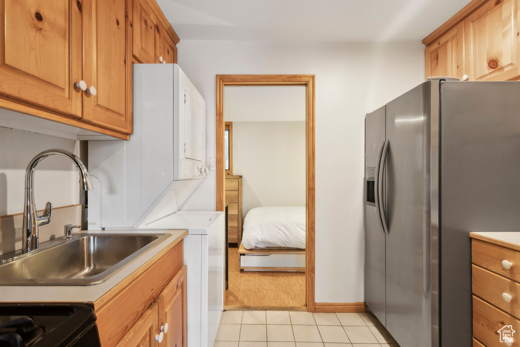 Kitchen featuring stainless steel fridge with ice dispenser, a sink, light countertops, light tile patterned floors, and baseboards