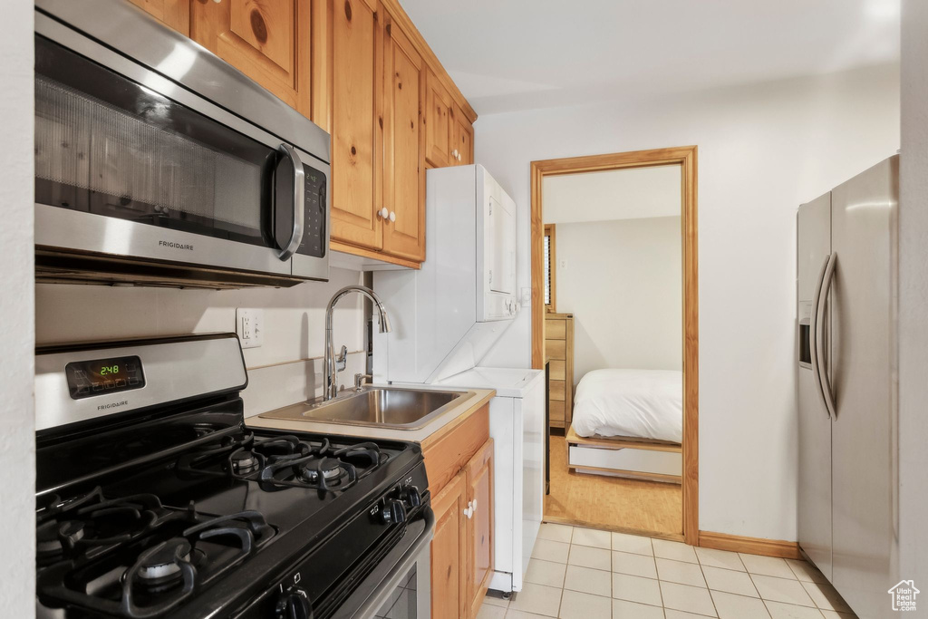 Kitchen featuring stainless steel appliances, a sink, light tile patterned floors, light countertops, and baseboards