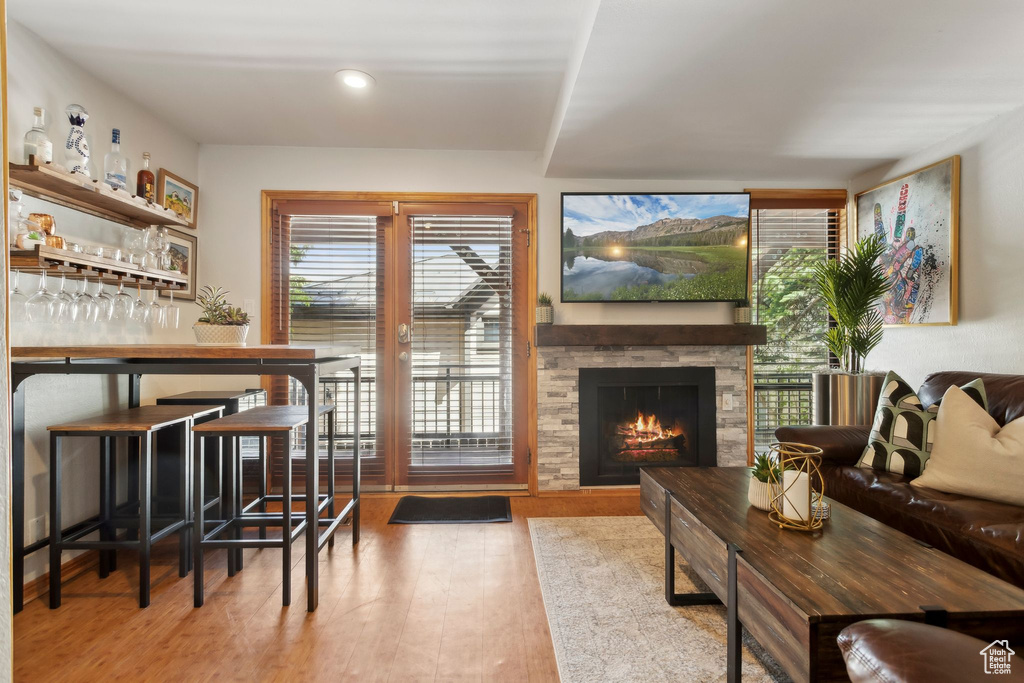 Living room featuring wood finished floors, a stone fireplace, a dry bar, and recessed lighting
