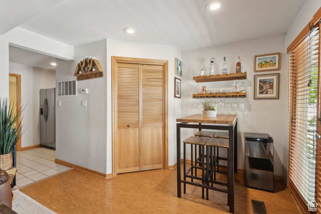 Kitchen featuring stainless steel refrigerator with ice dispenser, heating unit, baseboards, recessed lighting, and open shelves