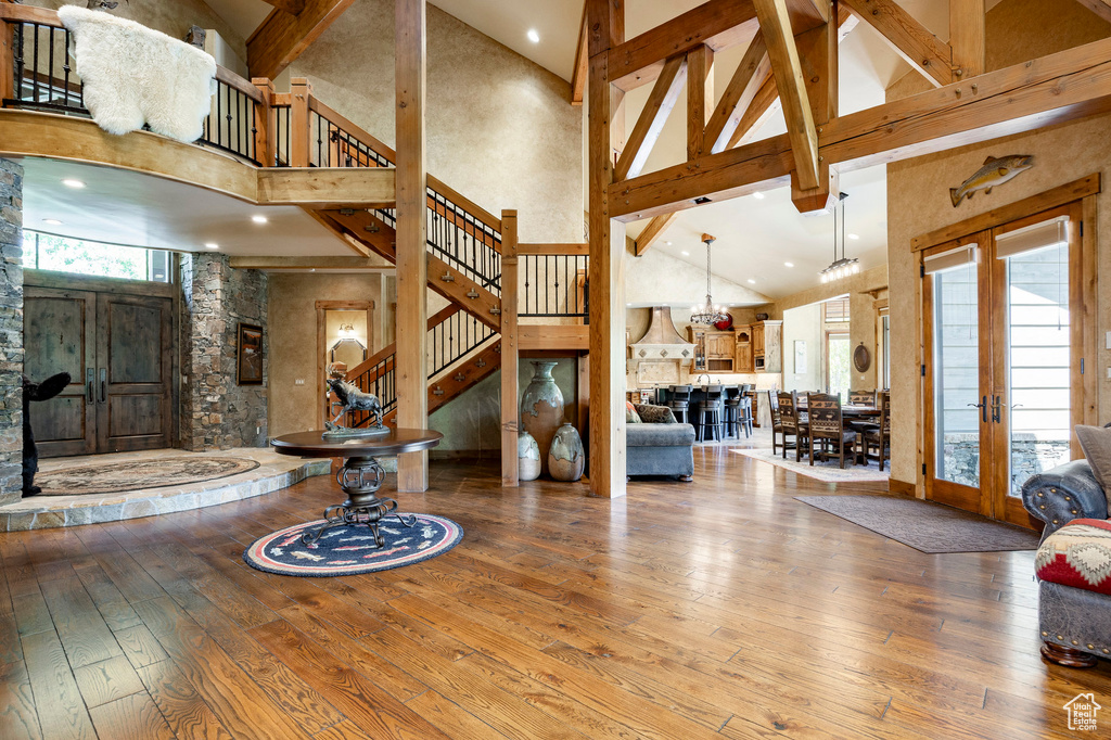 Living room with high vaulted ceiling, french doors, plenty of natural light, wood-type flooring, and stairway