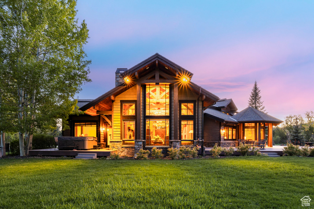 Back of house at dusk featuring a lawn, a chimney, and a porch