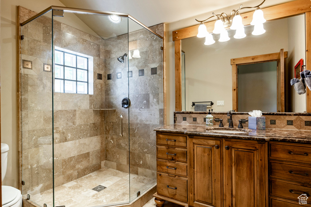 Bathroom with toilet, vanity, a shower stall, backsplash, and lofted ceiling