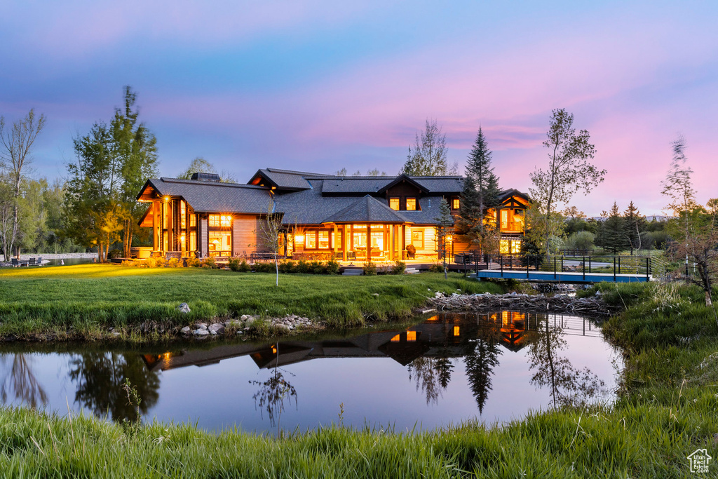 Rear view of house with a yard and a water view