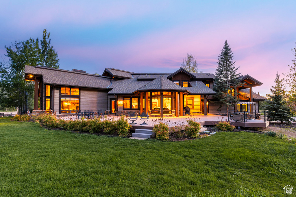 Back of property at dusk featuring a yard