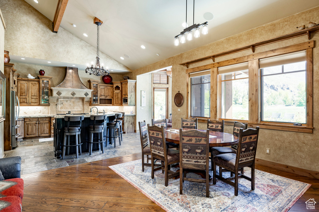 Dining room with a chandelier, high vaulted ceiling, wood finished floors, beam ceiling, and recessed lighting