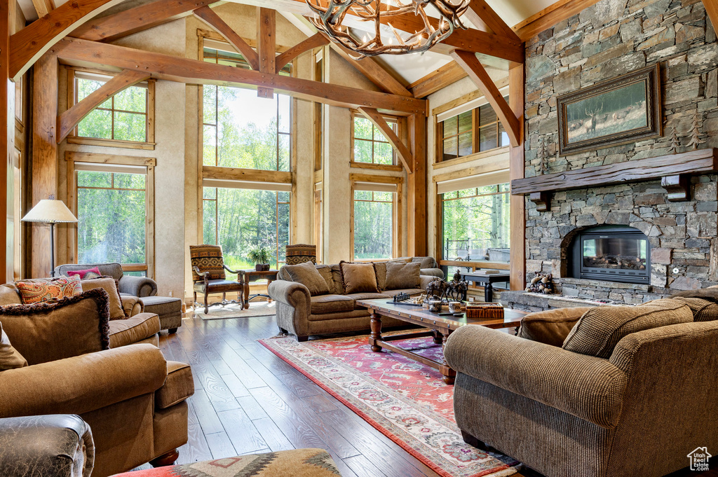 Living area with hardwood / wood-style flooring, a chandelier, high vaulted ceiling, beamed ceiling, and a fireplace
