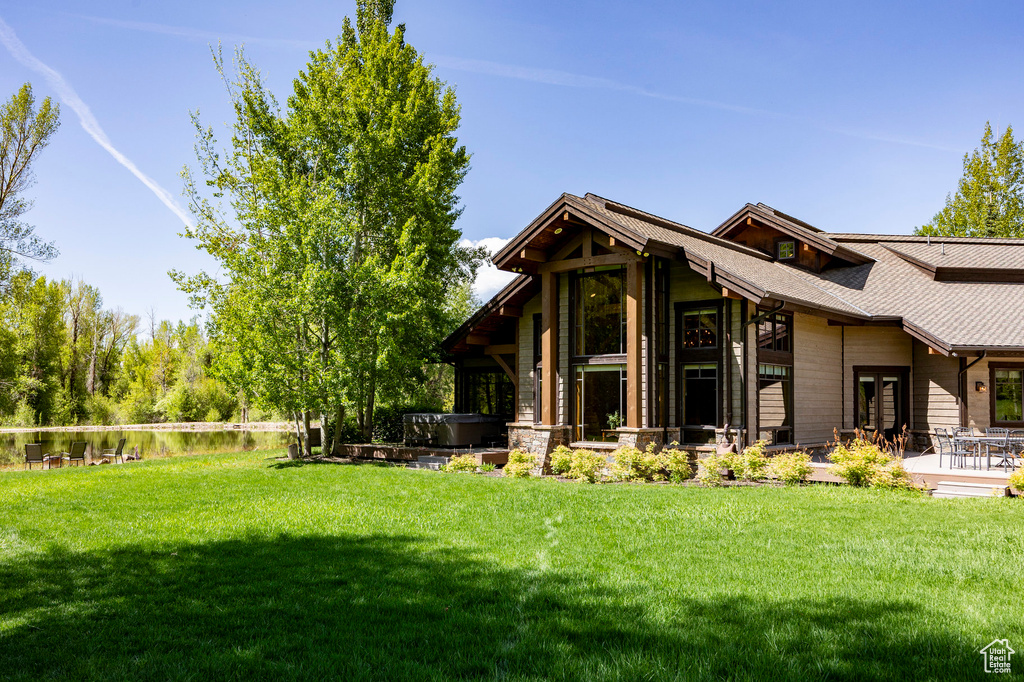 View of green lawn featuring a hot tub and a patio