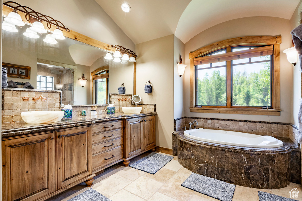 Full bath with lofted ceiling, a bath, double vanity, decorative backsplash, and a shower