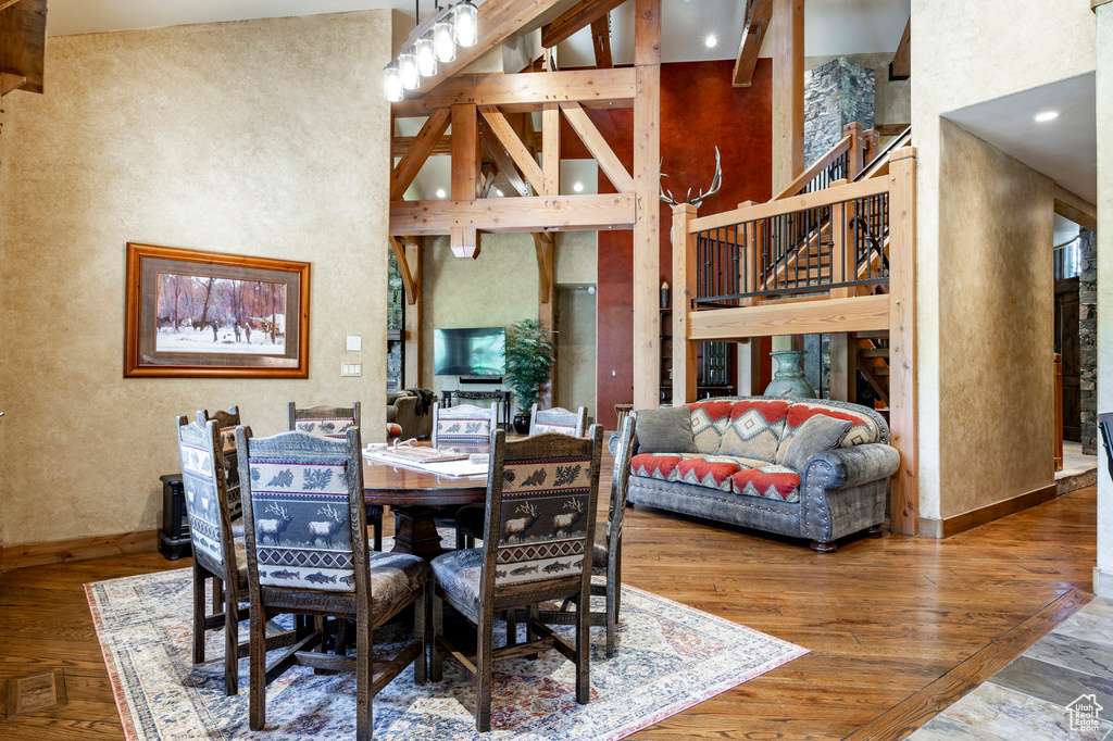 Dining area with a high ceiling, stairs, wood finished floors, baseboards, and a textured wall
