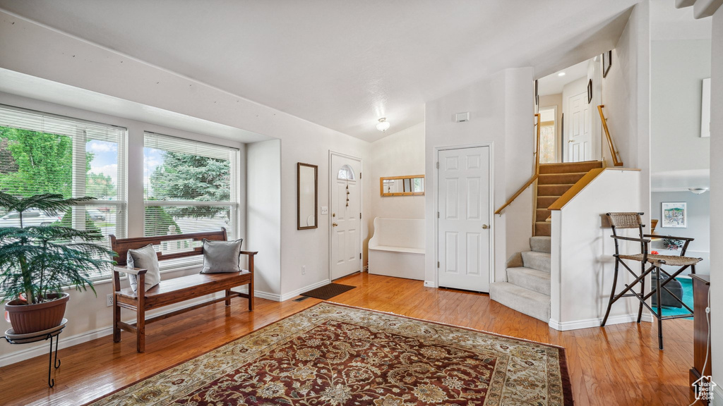 Foyer featuring wood finished floors, stairs, baseboards, and vaulted ceiling