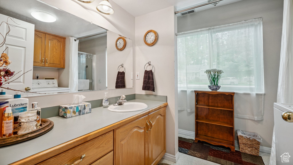 Full bathroom with vanity, washer / dryer, and baseboards