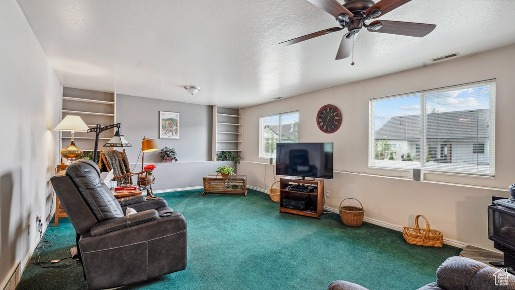 Carpeted living area featuring a textured ceiling, a wood stove, built in features, and baseboards