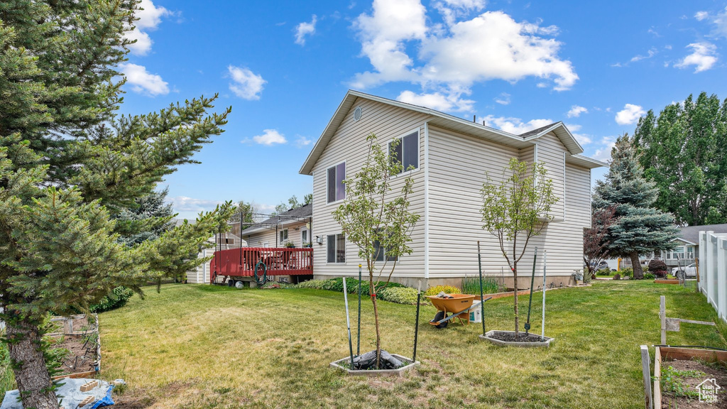 View of property exterior featuring a lawn and a wooden deck