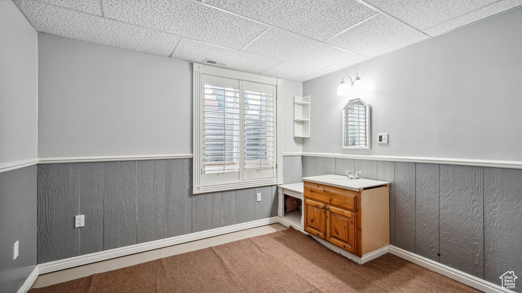 Bathroom with vanity, a paneled ceiling, a wainscoted wall, and baseboards