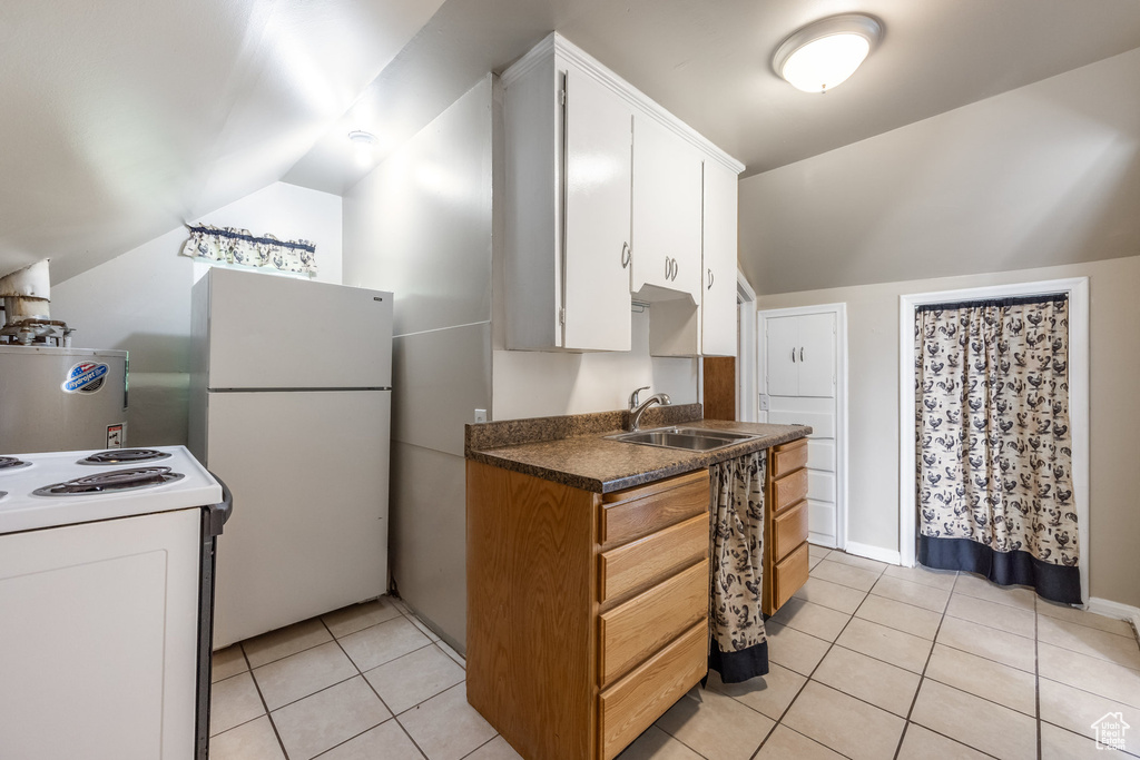 Kitchen with white appliances, a sink, vaulted ceiling, light tile patterned flooring, and white cabinetry