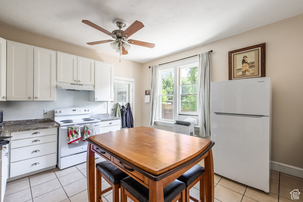 Kitchen featuring white appliances, under cabinet range hood, white cabinetry, a ceiling fan, and light tile patterned floors