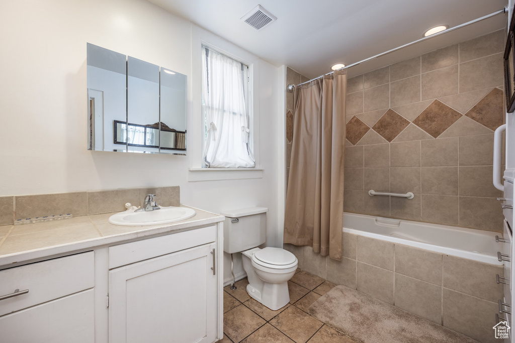 Bathroom with vanity, tiled shower / bath, tile patterned floors, and toilet