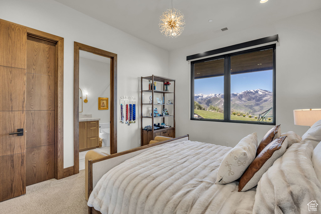 Bedroom with light carpet, a chandelier, and ensuite bath