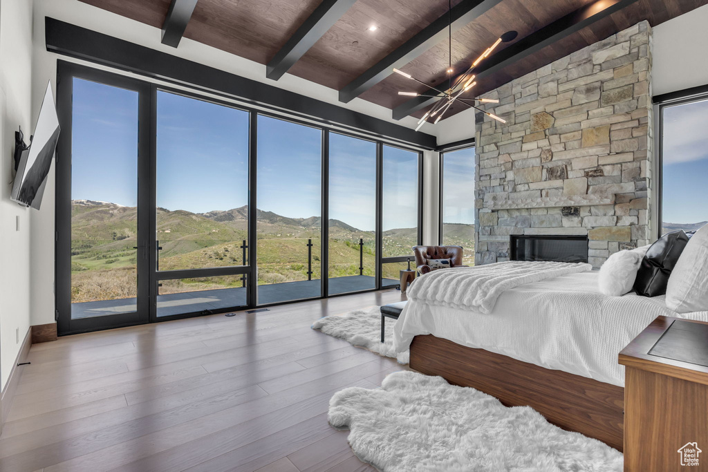 Bedroom with a mountain view, wooden ceiling with exposed beams, a chandelier, wood finished floors, and access to outside