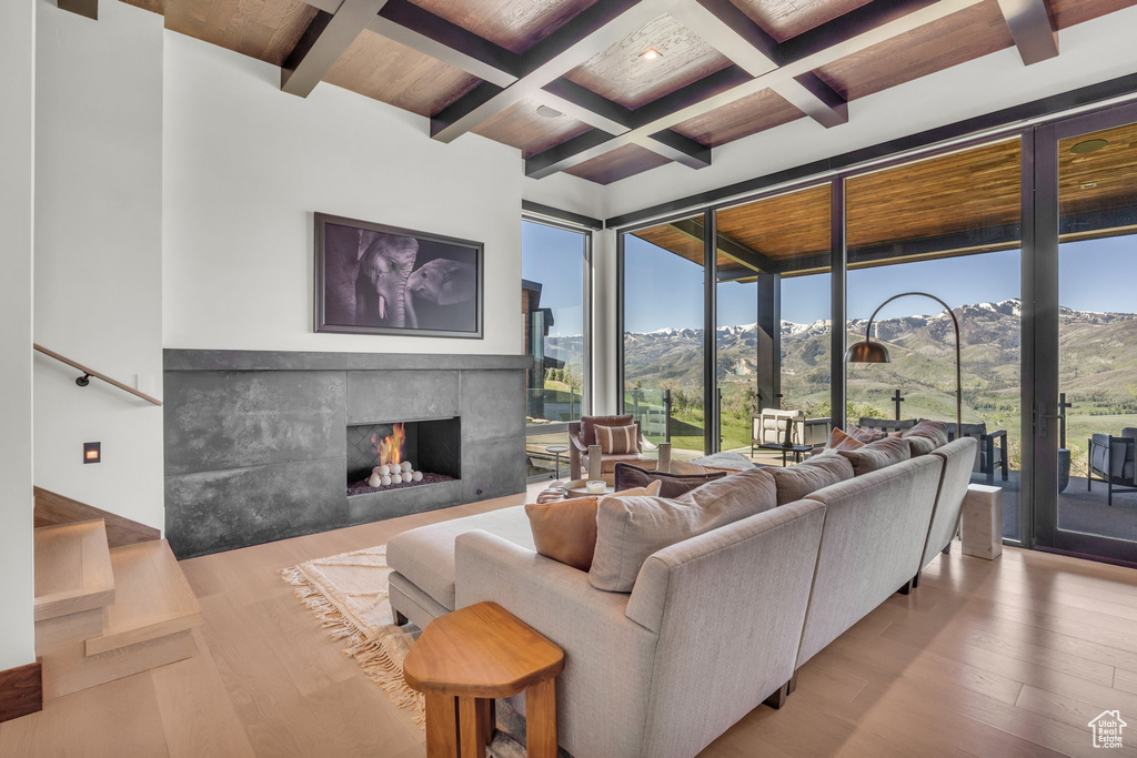 Living room with coffered ceiling, hardwood / wood-style flooring, beamed ceiling, a tile fireplace, and a mountain view