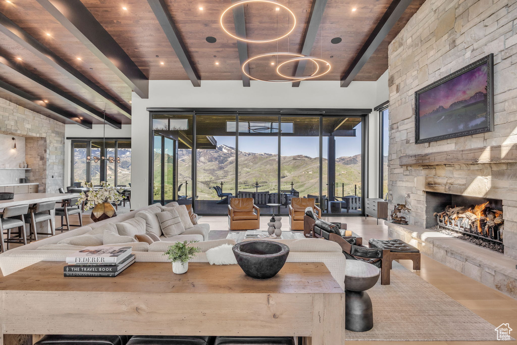 Living area featuring a stone fireplace, a chandelier, wood finished floors, a mountain view, and wooden ceiling