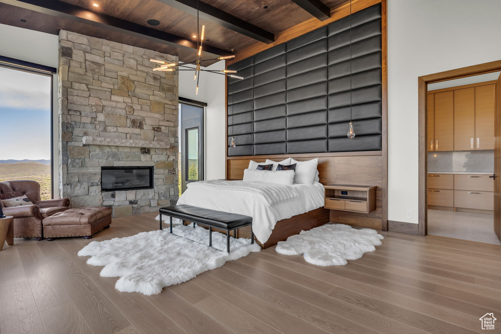 Bedroom featuring wood finished floors, wood ceiling with exposed beams, and a stone fireplace