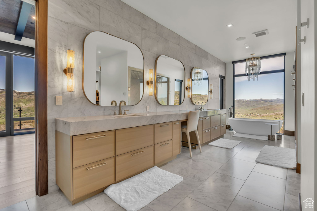 Bathroom featuring vanity, healthy amount of natural light, a freestanding tub, a chandelier, and recessed lighting