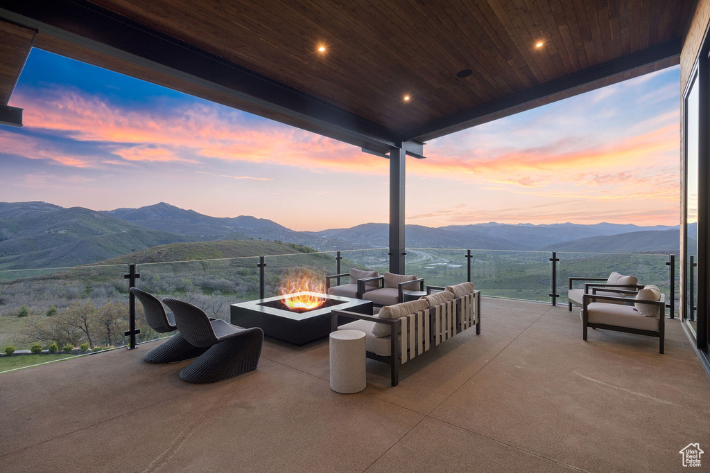 Patio terrace at dusk featuring a mountain view, an outdoor living space with a fire pit, and a patio area