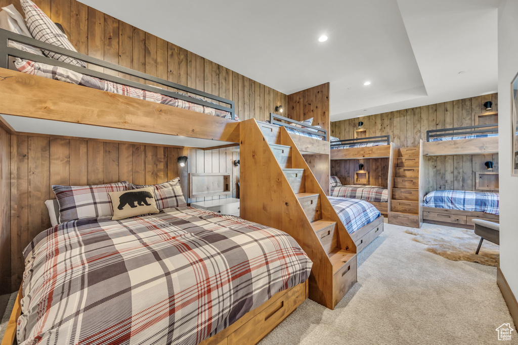 Carpeted bedroom with wood walls and recessed lighting