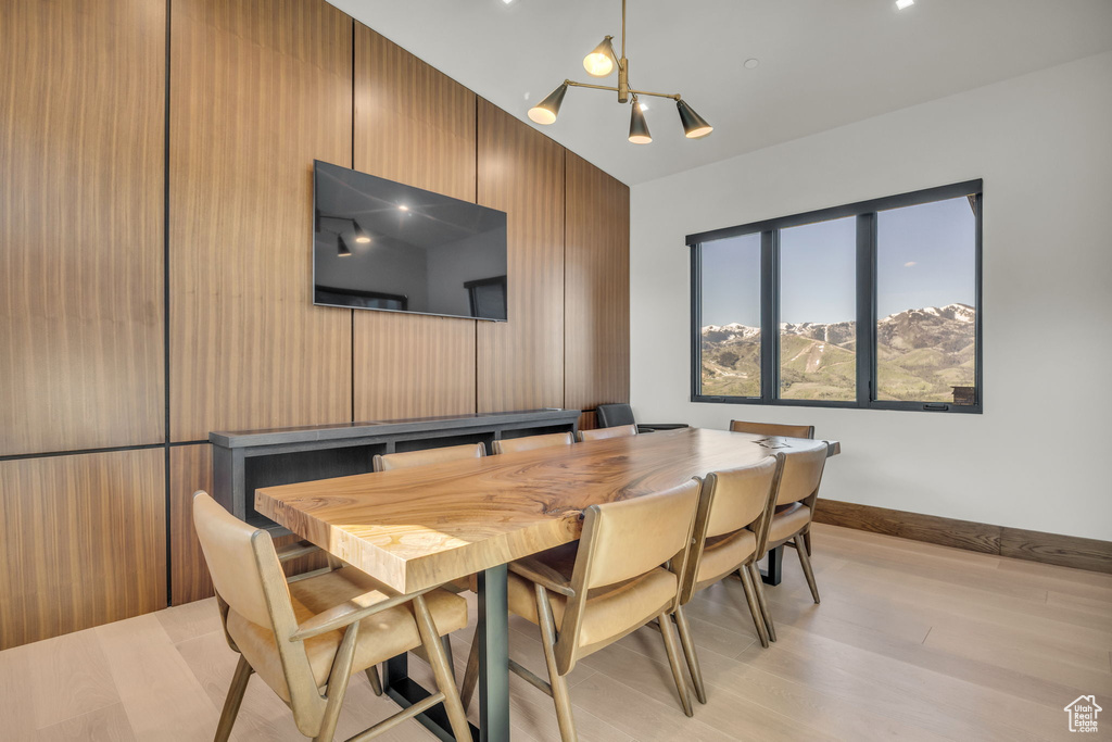 Dining space with a chandelier, light wood-style floors, vaulted ceiling, and baseboards