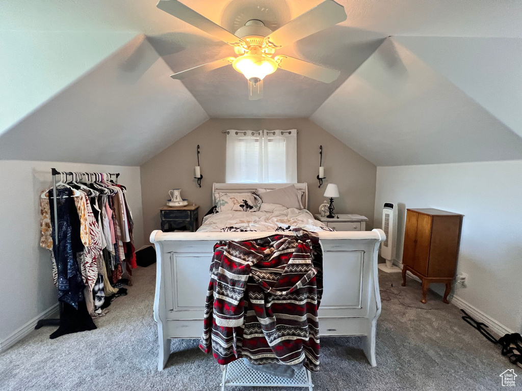 Carpeted bedroom with a ceiling fan, vaulted ceiling, and baseboards