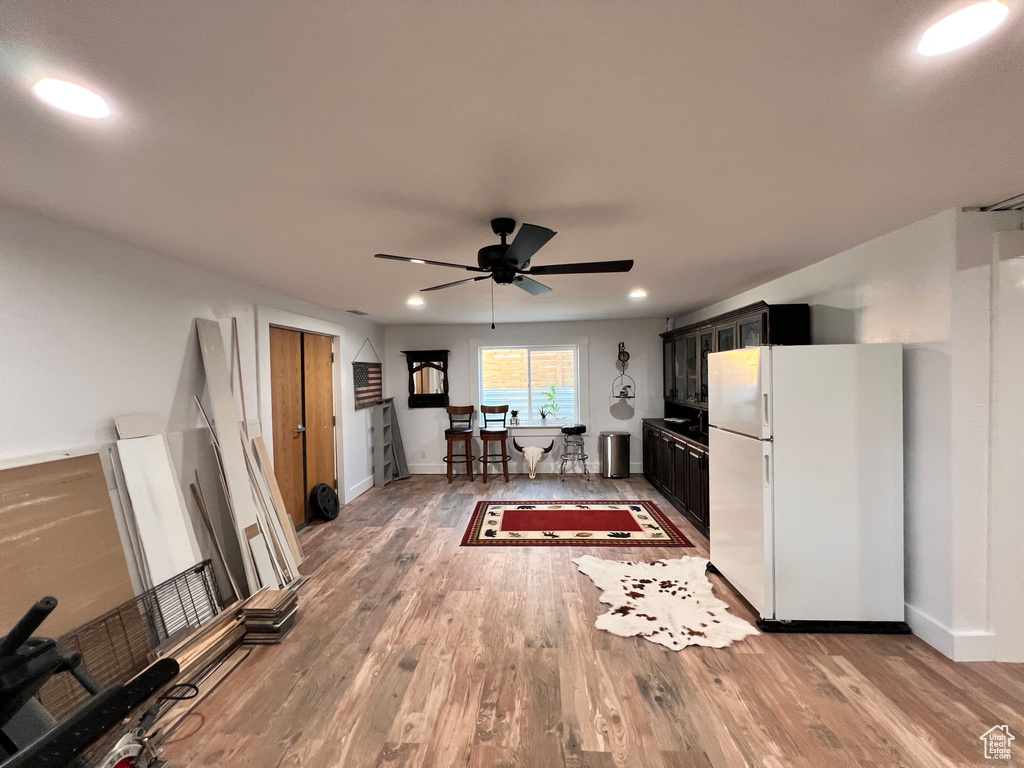 Kitchen featuring freestanding refrigerator, a ceiling fan, light wood-style floors, dark cabinetry, and recessed lighting