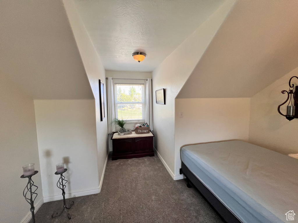 Bedroom featuring dark colored carpet and baseboards